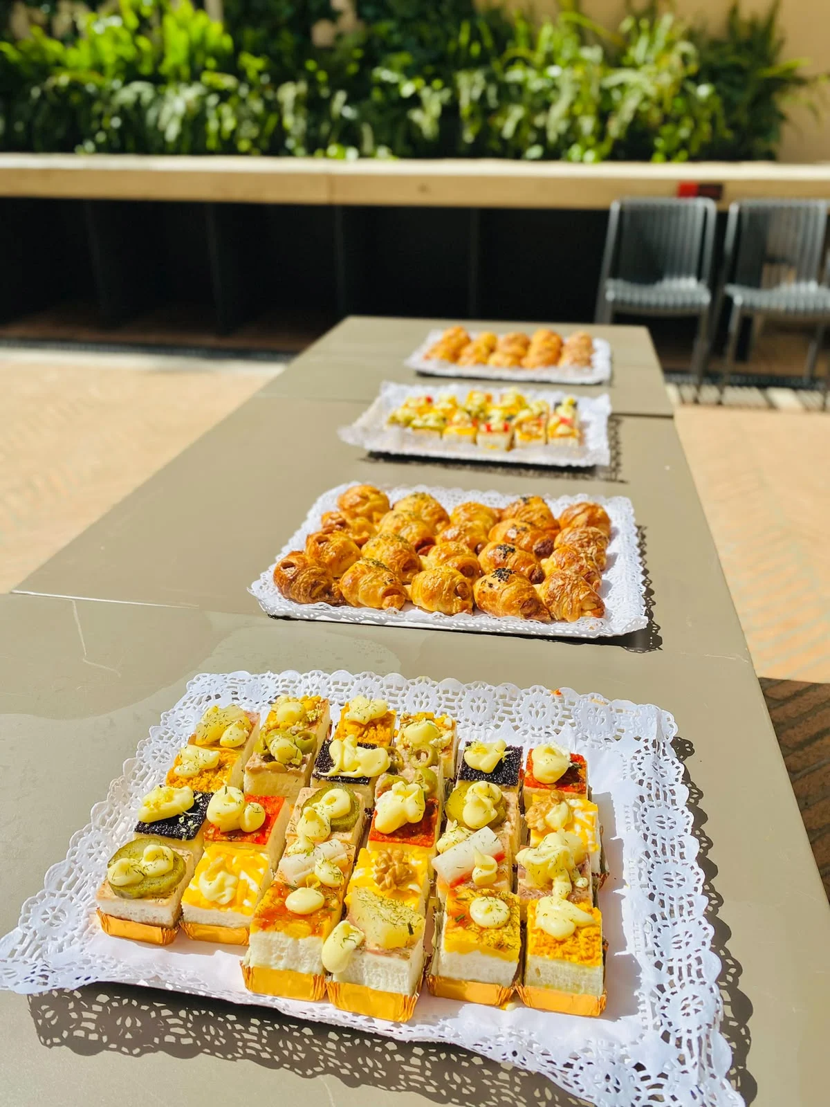 Mesa de cóctel con bandejas de canapés y mini croissants rellenos salados